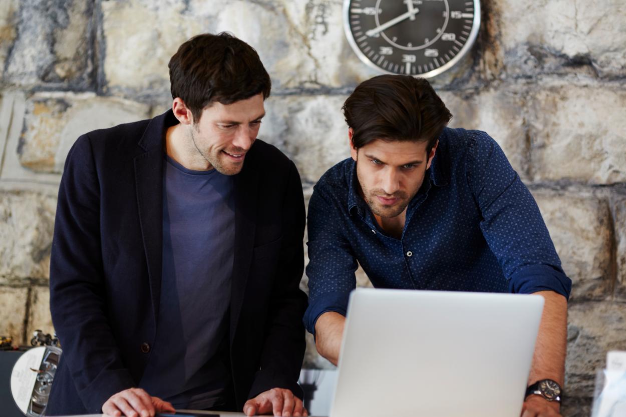 Two men viewing a computer screen, showcasing the flexibility and customization of Intraday Pricing Service delivery options.